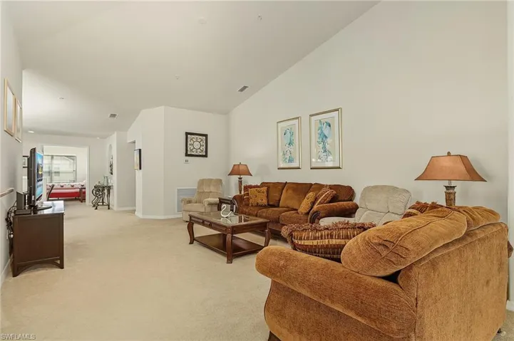 Living room with lofted ceiling and light carpet