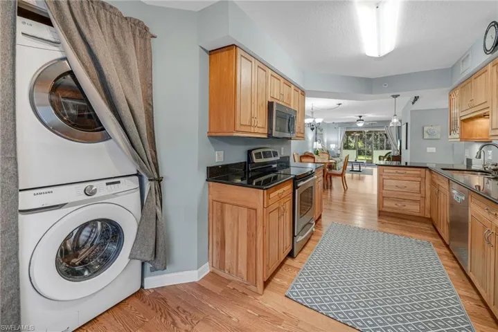 Clothes washing area featuring ceiling fan, sink, light hardwood / wood-style flooring, and stacked washing maching and dryer