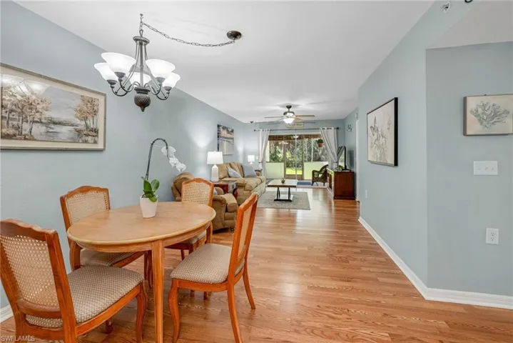 Dining area featuring light wood-type flooring and ceiling fan with chandelier