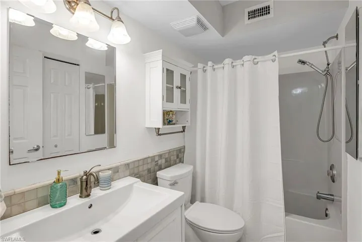 Full bathroom with vanity, shower / tub combo with curtain, tile walls, and toilet