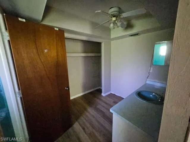 Bedroom with sink, ceiling fan, dark wood-type flooring, and a closet