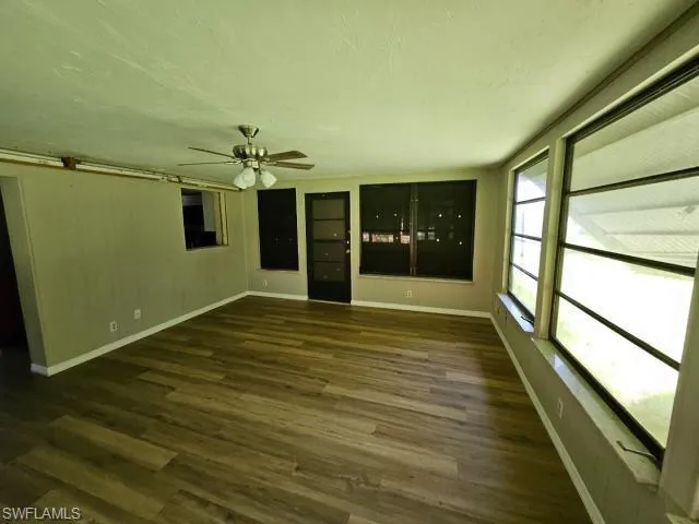 Unfurnished living room with dark hardwood / wood-style floors and ceiling fan
