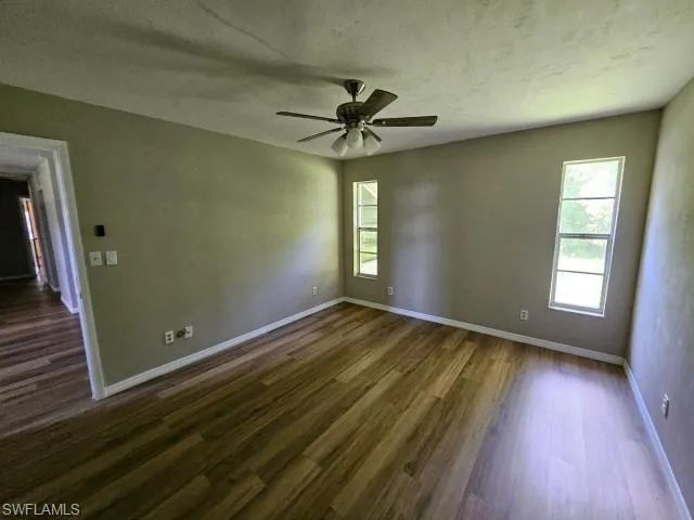 Empty room with dark hardwood / wood-style floors and ceiling fan