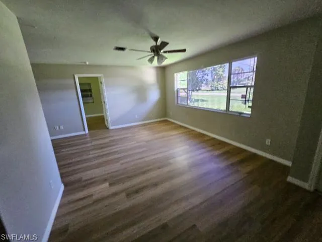 Unfurnished bedroom with dark wood-type flooring, a walk in closet, and ceiling fan