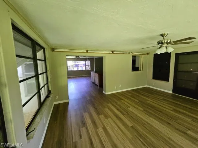 Unfurnished room with dark wood-type flooring and ceiling fan