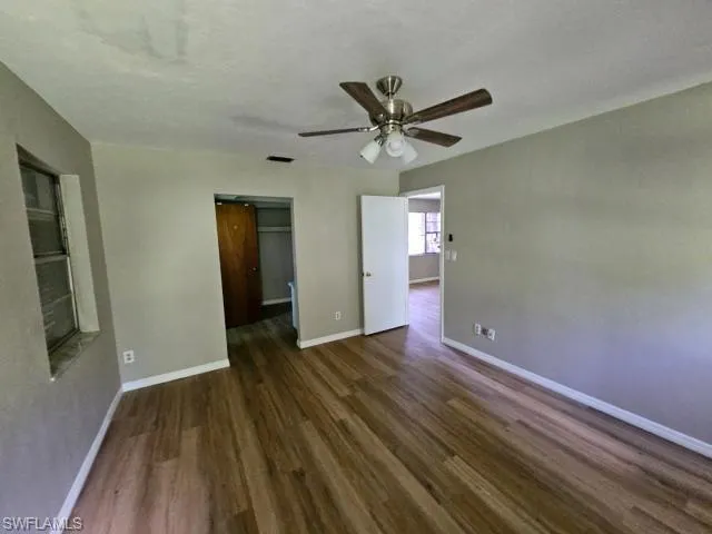 Unfurnished bedroom featuring a closet, a barn door, dark hardwood / wood-style flooring, a walk in closet, and ceiling fan