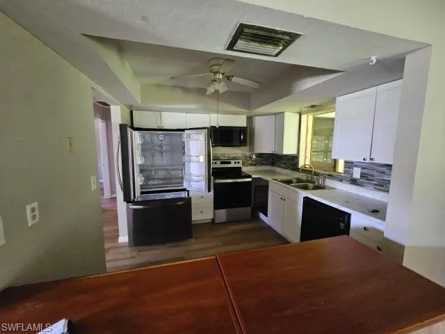 Kitchen featuring white cabinetry, ceiling fan, black appliances, and tasteful backsplash