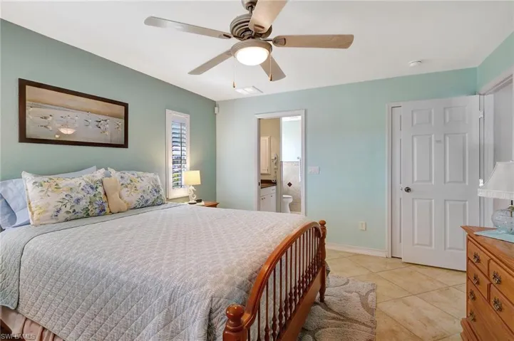 Tiled bedroom with ceiling fan and ensuite bath