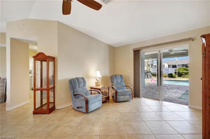 Living area with vaulted ceiling, ceiling fan, and light tile patterned flooring