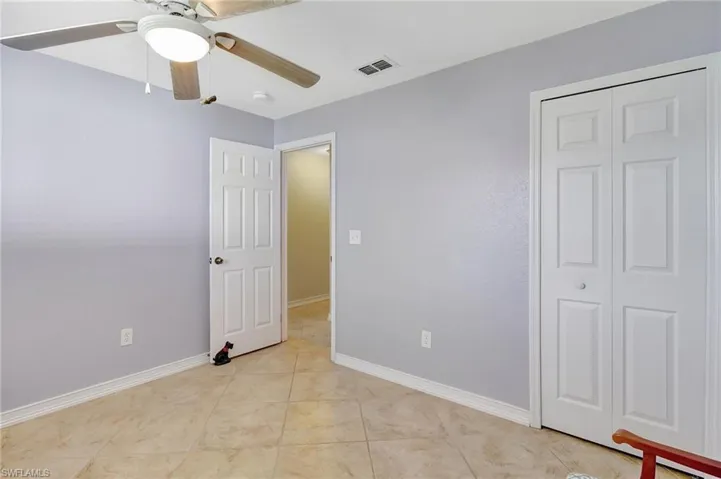 Unfurnished bedroom featuring light tile patterned floors, a closet, and ceiling fan