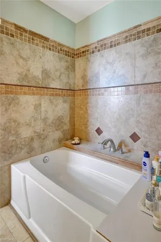 Bathroom with a bathing tub, tile patterned flooring, and tile walls
