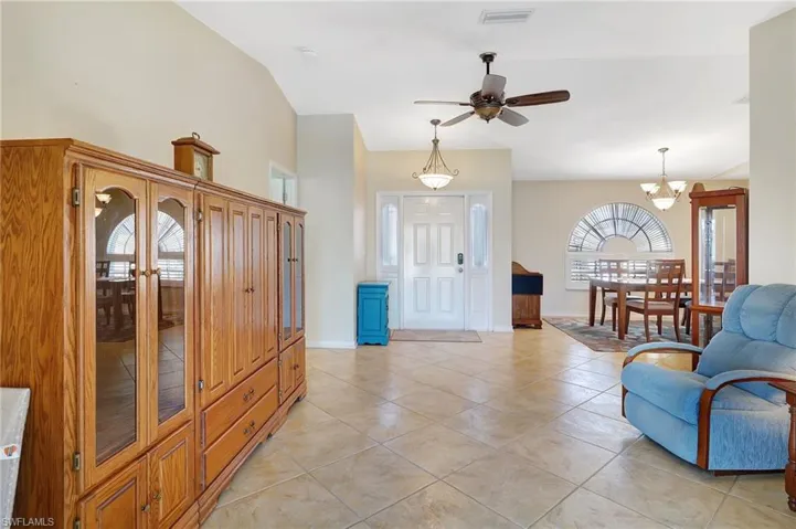 Tiled foyer entrance featuring ceiling fan with notable chandelier and lofted ceiling