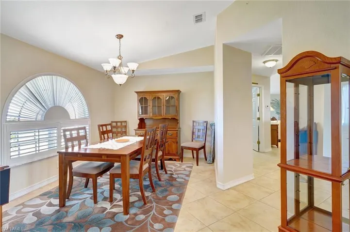 Dining room featuring light tile patterned floors, a chandelier, and vaulted ceiling