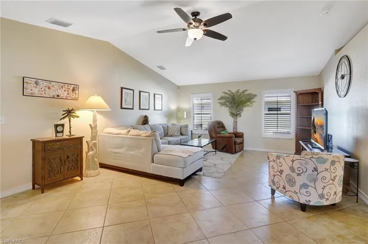 Tiled living room featuring ceiling fan and lofted ceiling