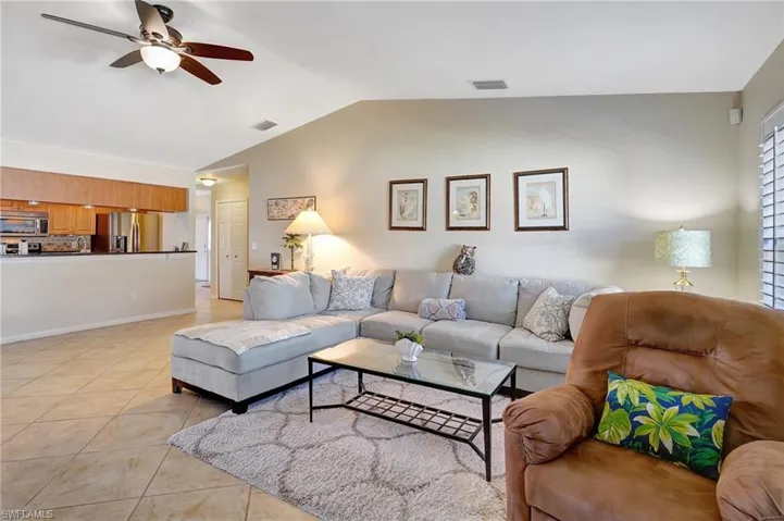 Tiled living room with ceiling fan and lofted ceiling