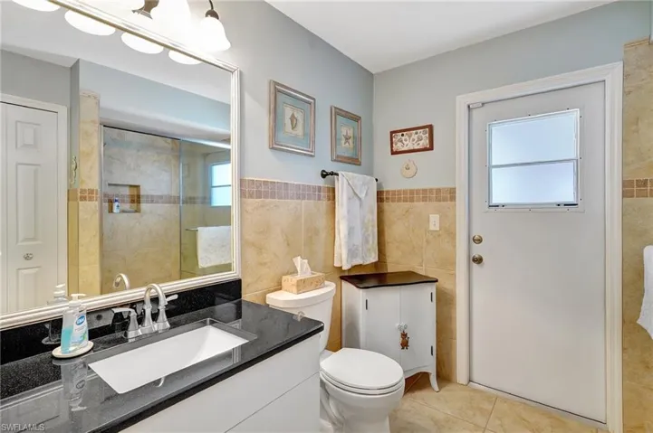 Bathroom featuring vanity, tile patterned floors, toilet, tile walls, and an enclosed shower