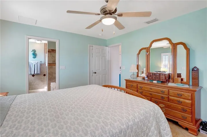 Tiled bedroom with connected bathroom and ceiling fan