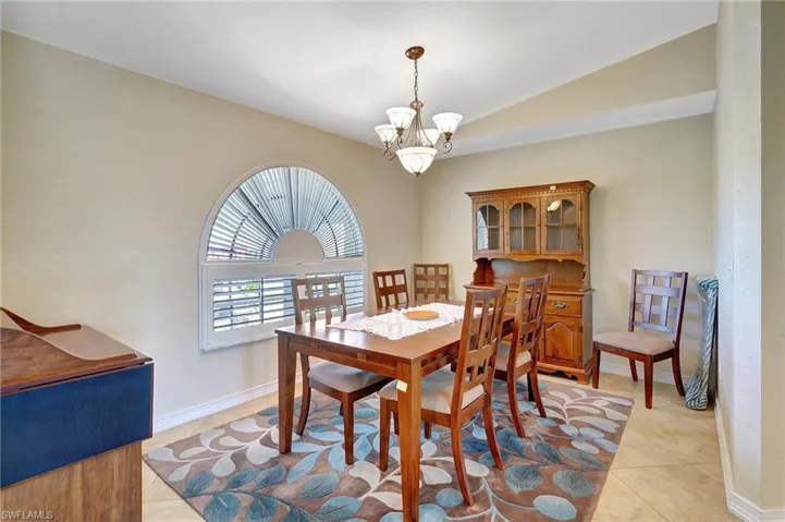 Tiled dining space featuring vaulted ceiling and an inviting chandelier