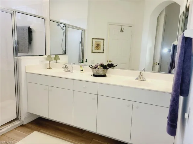 Bathroom with hardwood / wood-style floors, a shower with shower door, and vanity
