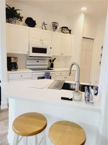 Kitchen featuring light hardwood / wood-style flooring, white cabinetry, a kitchen breakfast bar, and white range oven