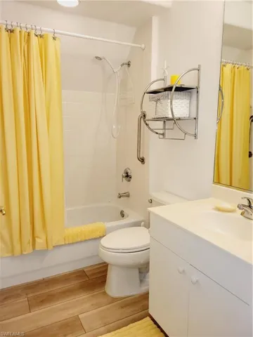 Full bathroom featuring shower / tub combo with curtain, wood-type flooring, vanity, and toilet