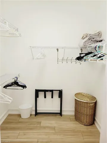Walk in closet with hardwood / wood-style flooring