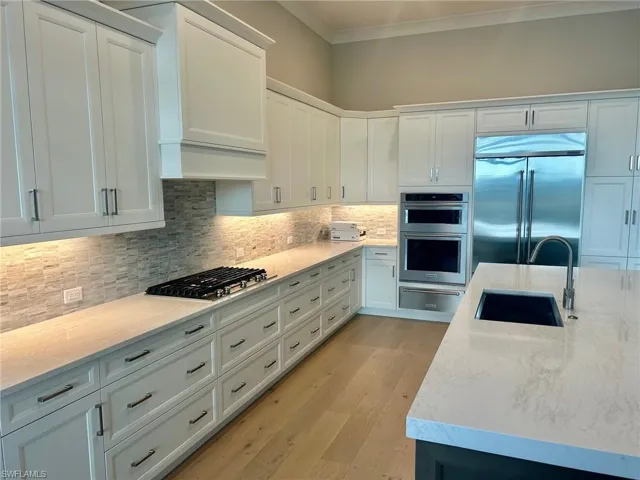 Kitchen with light hardwood / wood-style flooring, stainless steel appliances, sink, and white cabinets