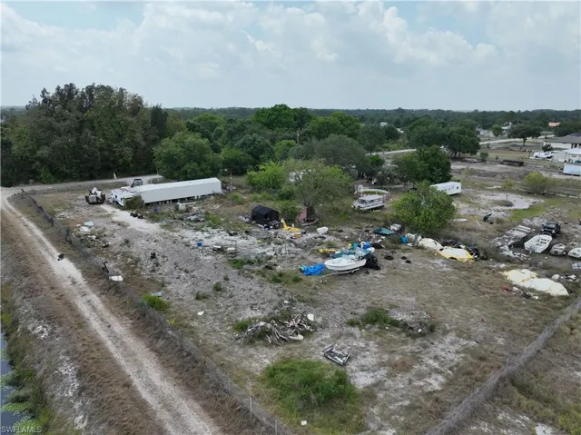 Expansive land parcel featuring a perimeter fence, a dirt access road, and mature trees on the property boundary
