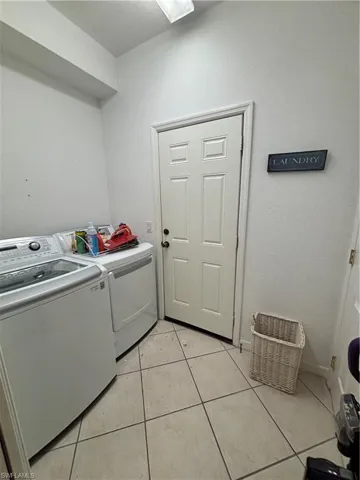 Laundry area featuring light tile patterned floors and washing machine and clothes dryer