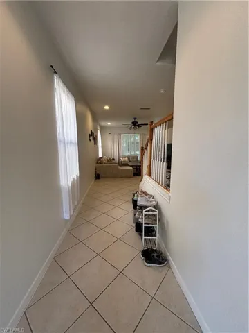 Hallway with light tile patterned floors, plenty of natural light, and stairway