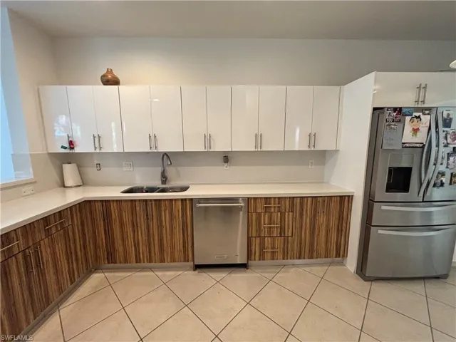Kitchen with appliances with stainless steel finishes, brown cabinets, white cabinets, modern cabinets, and light tile patterned floors
