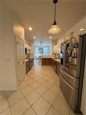 Kitchen with fridge, light countertops, light tile patterned flooring, pendant lighting, and recessed lighting