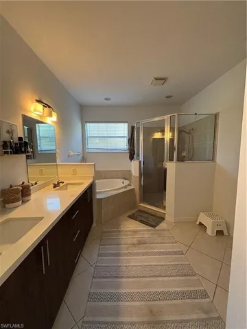 Bathroom with light tile patterned floors, double vanity, a bath, and a stall shower