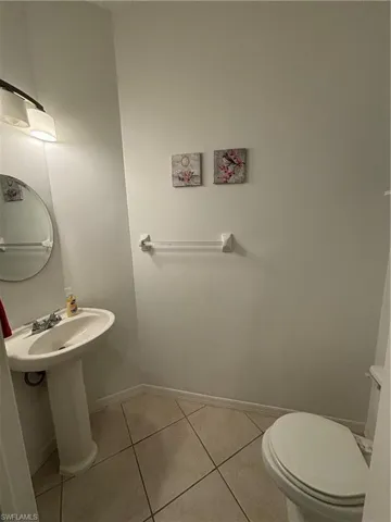 Half bath with light tile patterned floors and baseboards