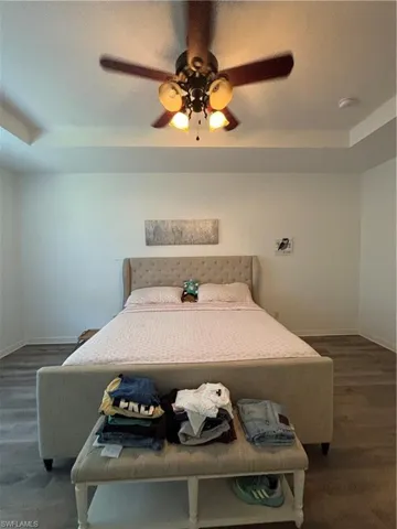 Bedroom featuring ceiling fan, a textured ceiling, dark wood-style floors, and a tray ceiling
