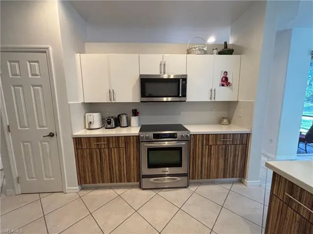 Kitchen featuring white cabinetry, stainless steel appliances, brown cabinets, and modern cabinets