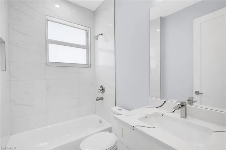 Full bathroom featuring tiled shower / bath combo, vanity, and toilet