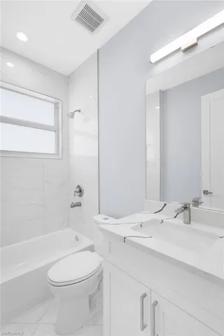 Full bathroom featuring tiled shower / bath combo, vanity, and toilet