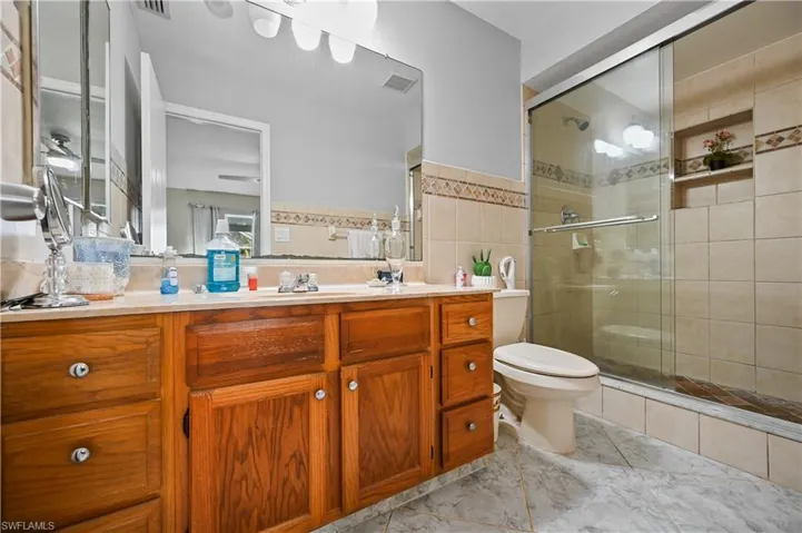 Full bath featuring vanity, a shower stall, and tile walls
