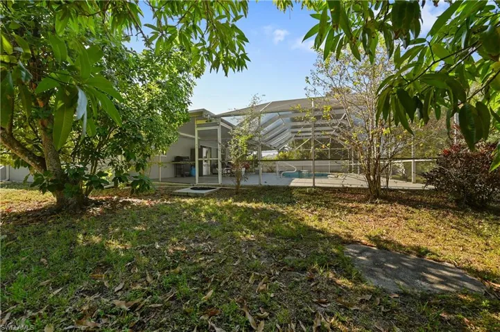 Rear view of house featuring an outdoor pool, a sunroom, a lanai, a patio, and a yard