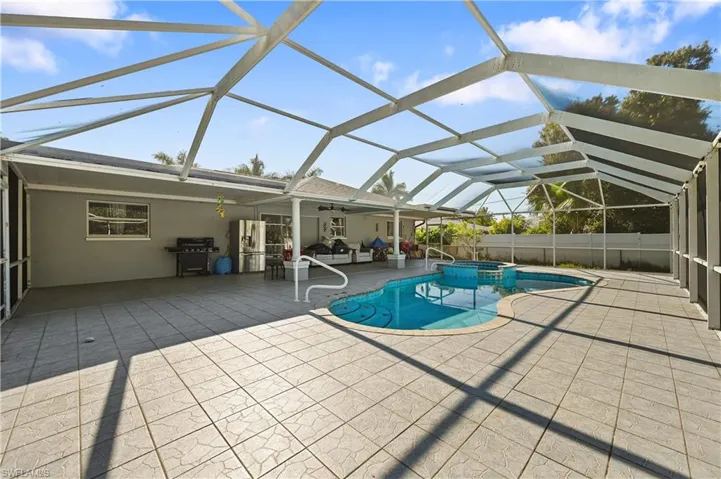 View of swimming pool featuring a sunroom, a lanai, a patio, and grilling area