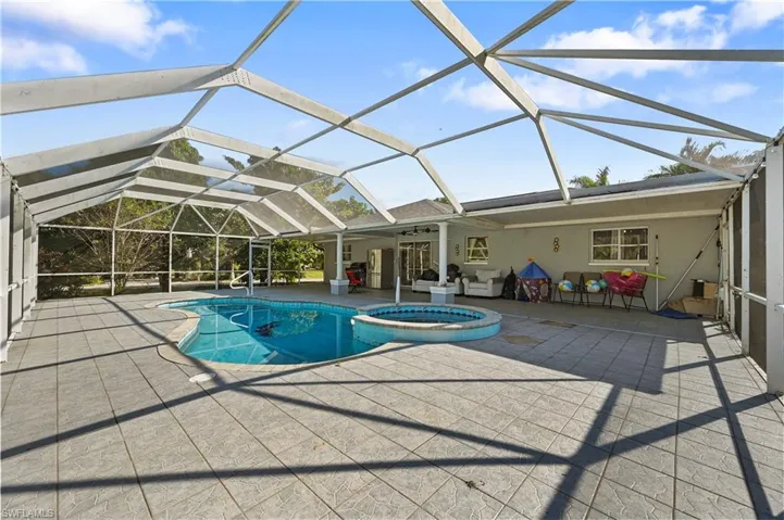 View of pool featuring a sunroom, glass enclosure, a pool with connected hot tub, and a patio area