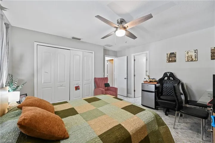 Bedroom with freestanding refrigerator, a closet, a ceiling fan, and an office area