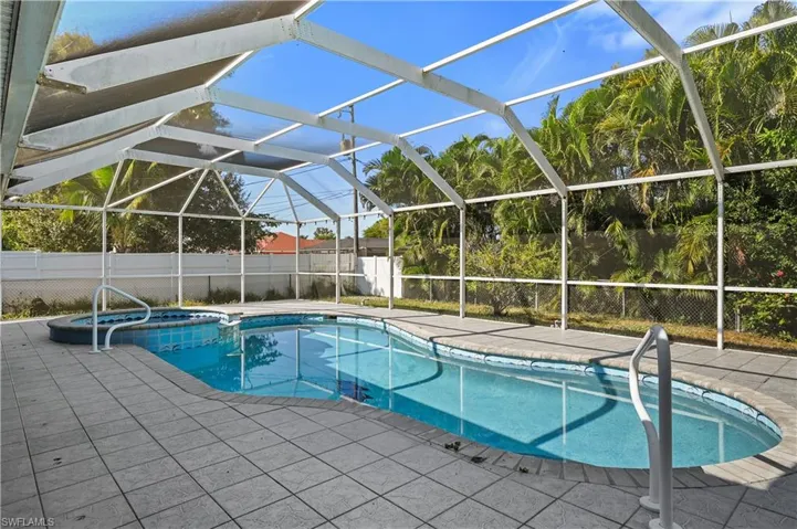 View of swimming pool featuring glass enclosure, a pool with connected hot tub, a patio area, and a sunroom