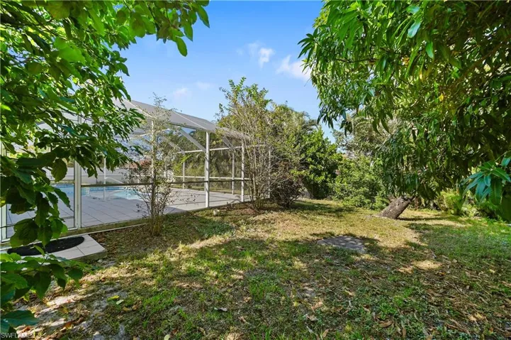 View of green lawn with a sunroom, a lanai, and an outdoor pool