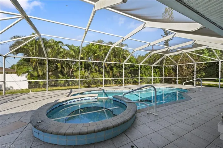 View of pool featuring a lanai, a pool with connected hot tub, a patio, and a sunroom