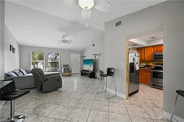 Living room featuring lofted ceiling, light tile patterned floors, and ceiling fan