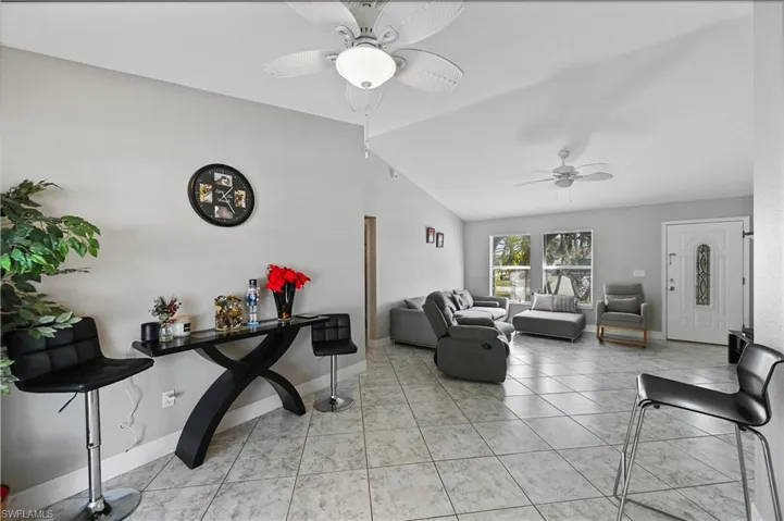 Living area featuring lofted ceiling, light tile patterned floors, and ceiling fan