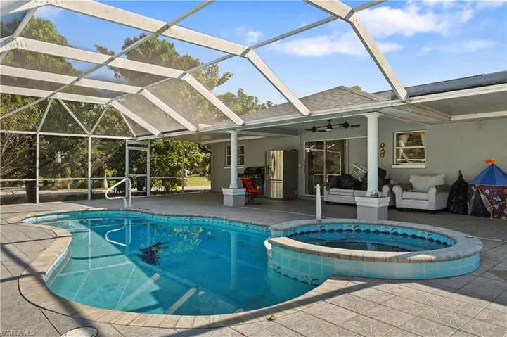View of pool featuring glass enclosure, a patio, a sunroom, and a pool with connected hot tub
