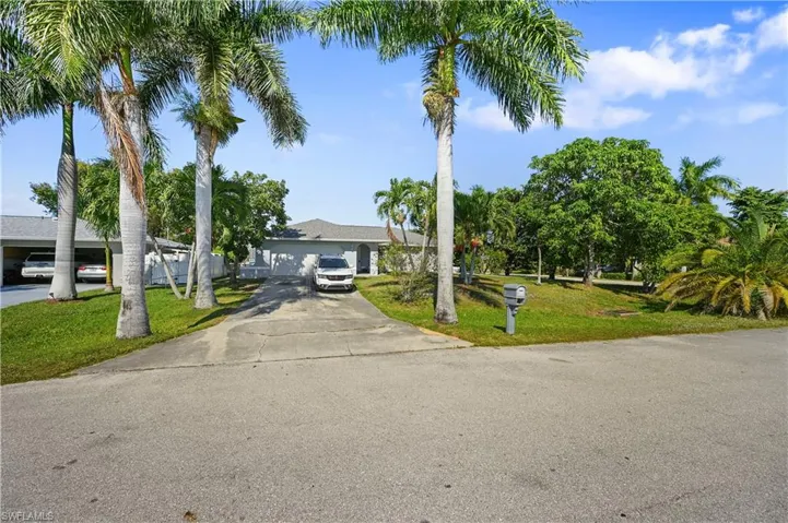 View of front of home with concrete driveway and a front lawn